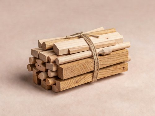 Soft-lit 3D render of bundled beech, ash, and oak joinery offcuts tied with jute twine on a blush surface